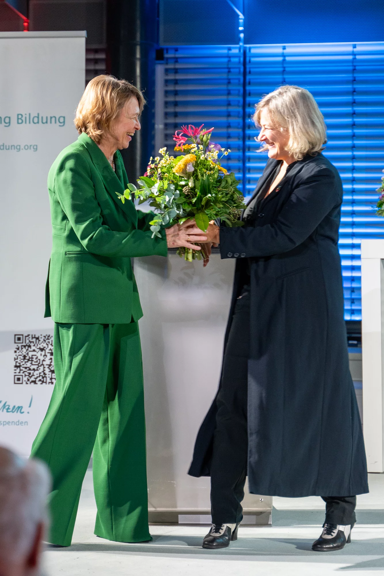 Katja Hintze beim Überreichen des Blumenstraußes an lke Büdenbender - - Förderpreis "Verein(t) für gute Kita und Schule" 2024