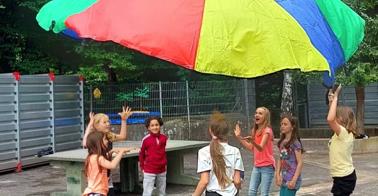 Kindr spielen mit einem Regenbogentuch - Unsere Startchancen-Programm Empfehlungen